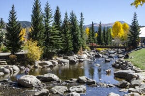 Breckenridge, Colorado, USA - October 12, 2015: Residents of Breckenridge enjoy a spectacular Fall afternoon by the Blue River in the Blue River Plaza and Riverwalk located in the town of Breckenridge, Colorado which was created in November 1859 by General George E. Spencer. The Blue River flows through a riverfront park created as a revitalization project by the town of Breckenridge. The historic Town of Breckenridge is the most populous municipality of Summit County, Colorado, United States. The town is located at the base of the Tenmile Range. Summer in Breckenridge attracts outdoor enthusiasts with hiking trails, wildflowers, fly-fishing in the Blue River, mountain biking, nearby Lake Dillon for boating, white water rafting, alpine slides, and several shops up and down Main Street.