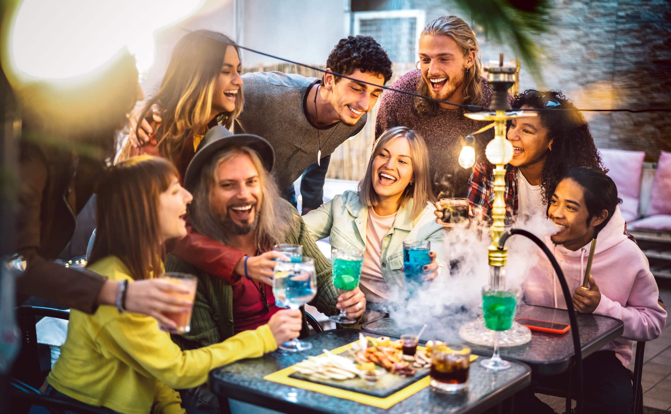 Happy friends having fun drinking cocktails and smoking weed together